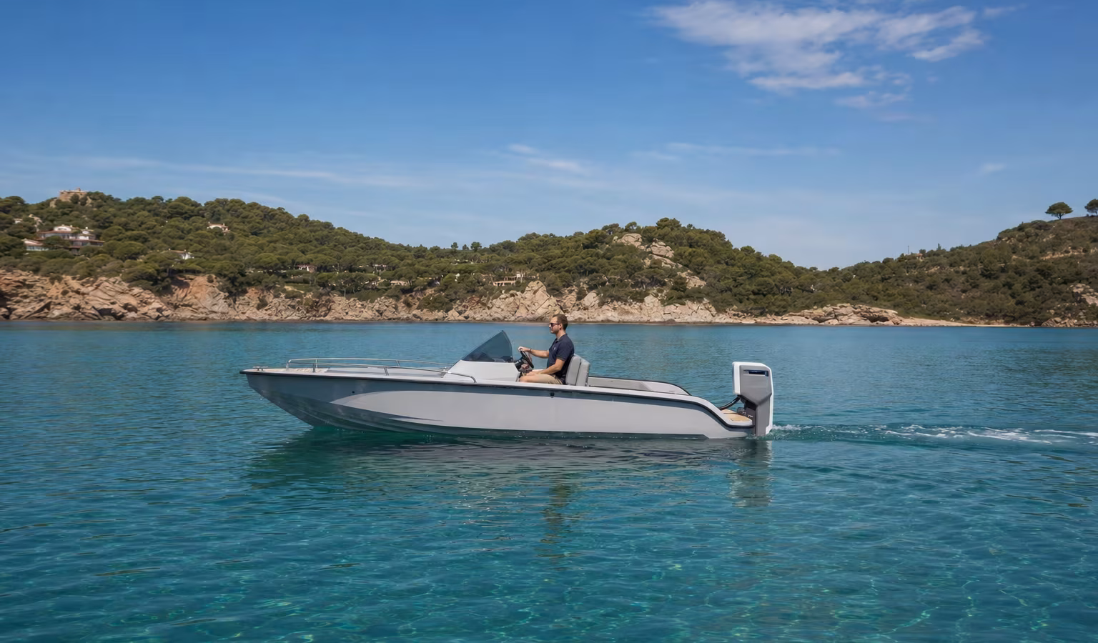 Modernes Motorboot mit Elektro-Außenborder gleitet leise über klares Wasser vor einer Küste