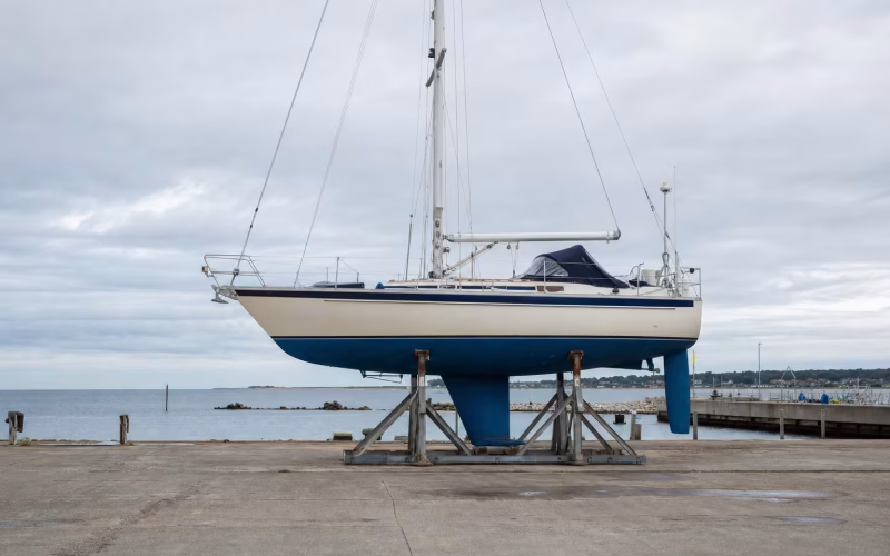 Segelyacht steht aufgebockt im Bootslager, der Kiel unter der Wasserlinie ist von der Seite gut sichtbar
