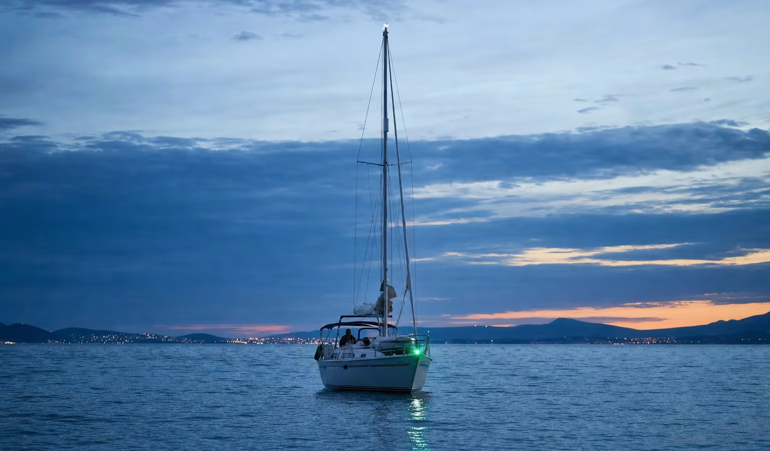 Segelyacht in der Dämmerung mit grün leuchtendem Steuerbord-Positionslicht am Bug