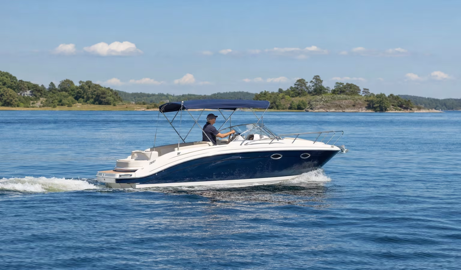 Motorboot gleitet sparsam bei moderater Fahrt über ruhiges Wasser vor einer Küste