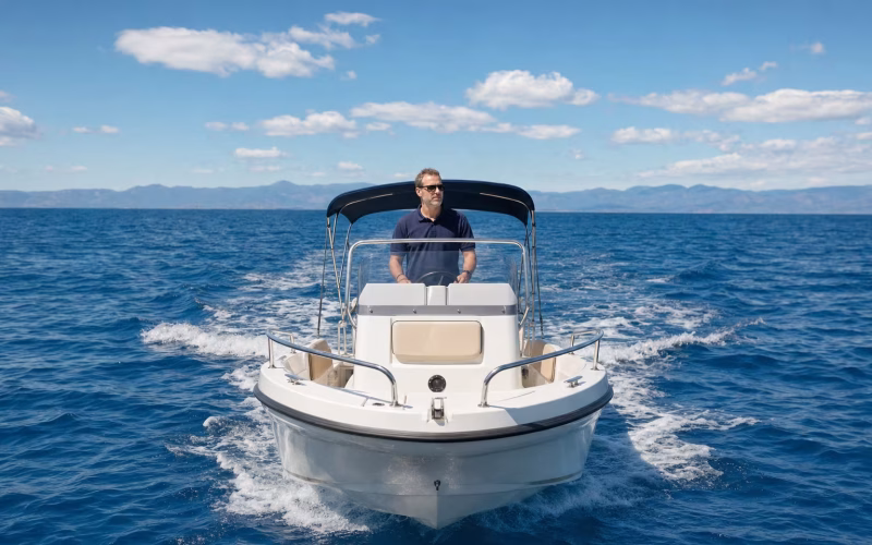Konzentrierter Skipper steuert ein Motorboot mit beiden Händen am Steuerrad bei klarer Sicht