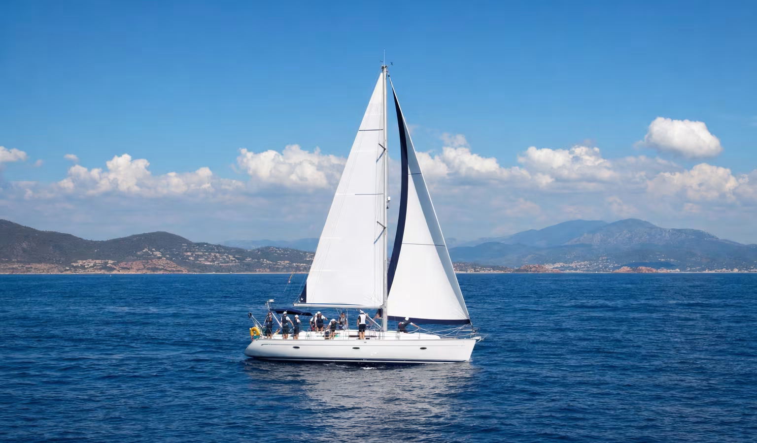 Segelyacht mit übender Crew auf einem Küstentörn auf offenem blauem Wasser