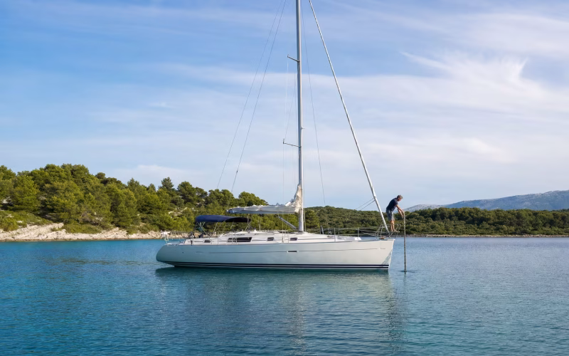 Segelyacht lässt in einer geschützten Bucht den Anker fallen, ein Crewmitglied am Bug