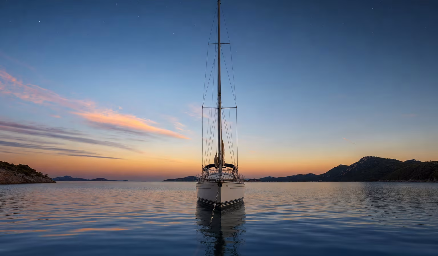 Segelyacht vor Anker in ruhiger Bucht in der Abenddämmerung