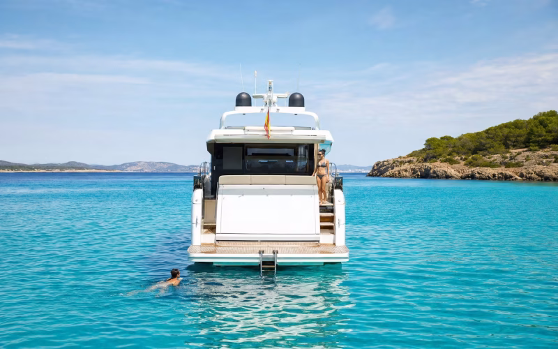 Yacht vor Anker in türkisblauer Bucht mit ausgeklappter Badeleiter und Schwimmer
