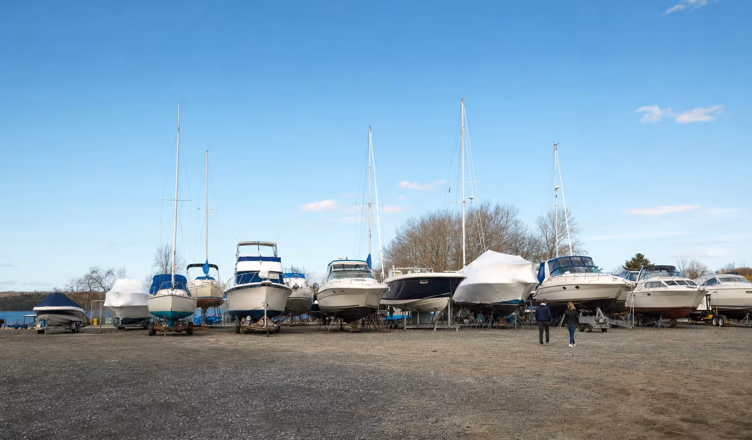 Reihen von Motorbooten und Segelyachten auf Trailern und Böcken an einem Lagerplatz zum Verkauf