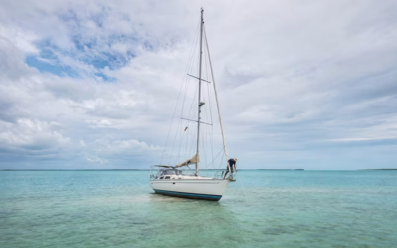 Segelyacht auf einer Sandbank in flachem Wasser, Crew prüft die Tiefe